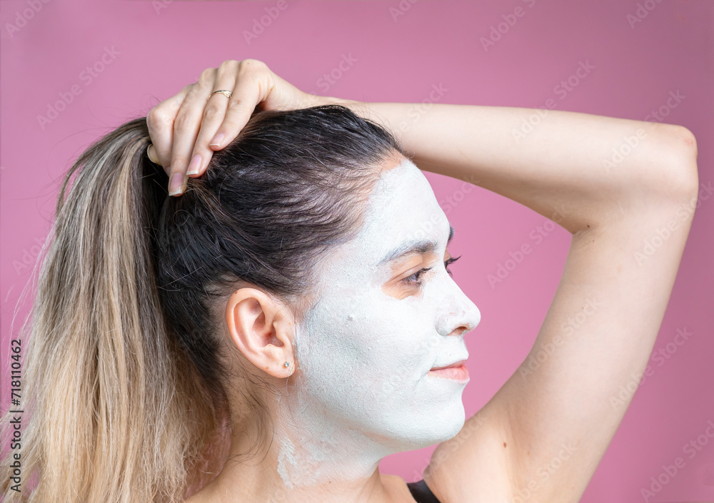 Naklejka premium Portrait of a woman with a cosmetic mask on her face. A cheerful woman with a white face.