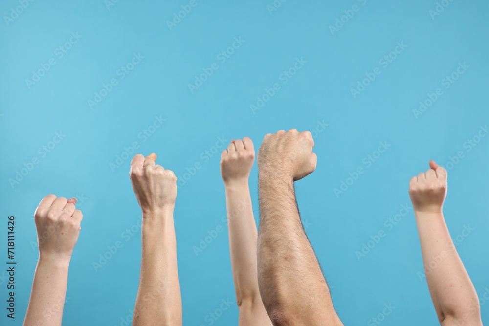 Strike. People showing clenched fists on light blue background, closeup Strike. People showing clenched fists on light blue background, closeup