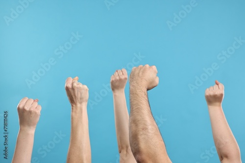 Strike. People showing clenched fists on light blue background, closeup