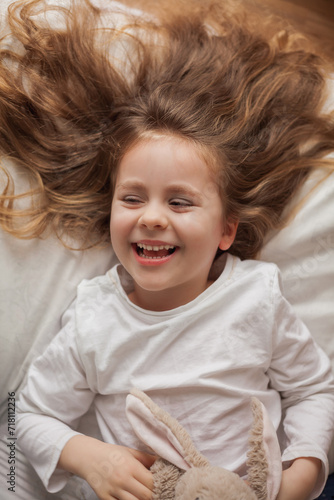 Adorable happy child. Portrait of little smiling cute girl with blue eyes and long hair. Cozy home.