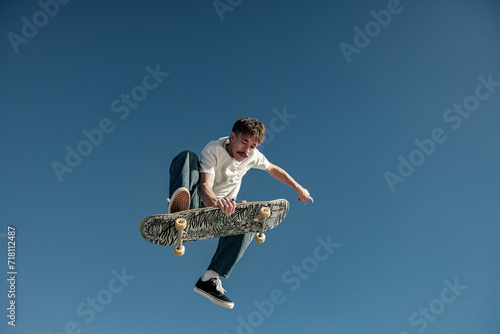 A young man doing tricks in the air on his skateboard at the skate park. Active sport concept