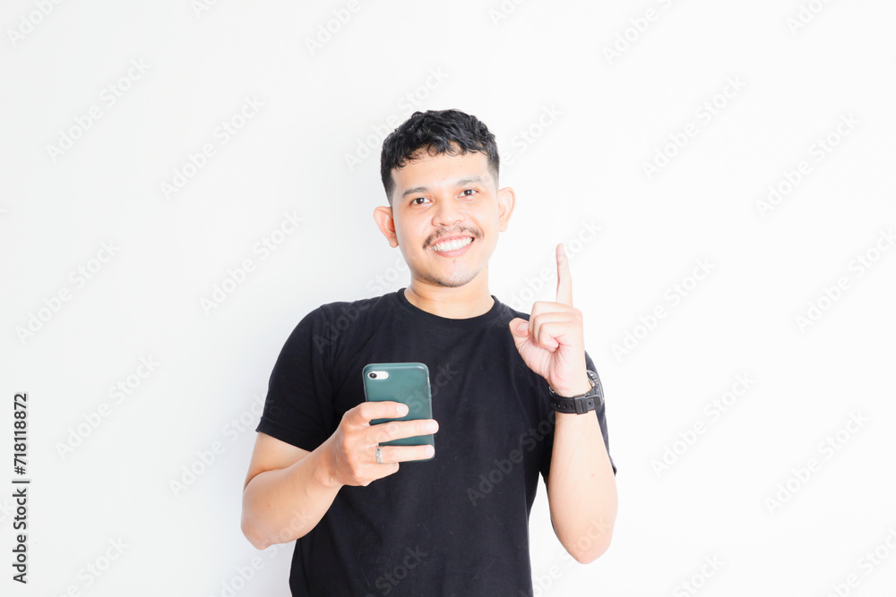 asian man showing happy expression while holding smartphone asian man showing happy expression while holding smartphone