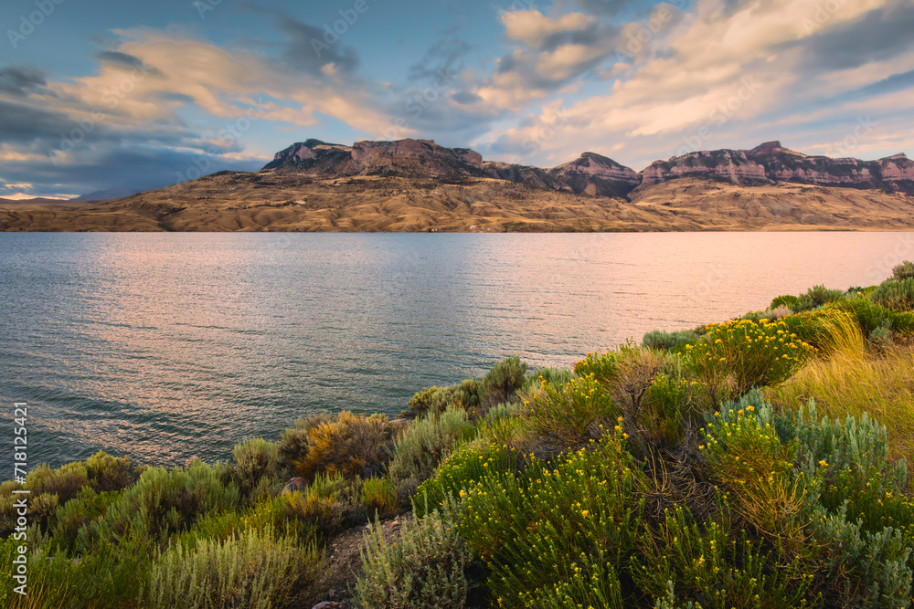 Fototapeta premium Water reservoir and river flanked by foothills and wild sagebrush. Cody, USA.