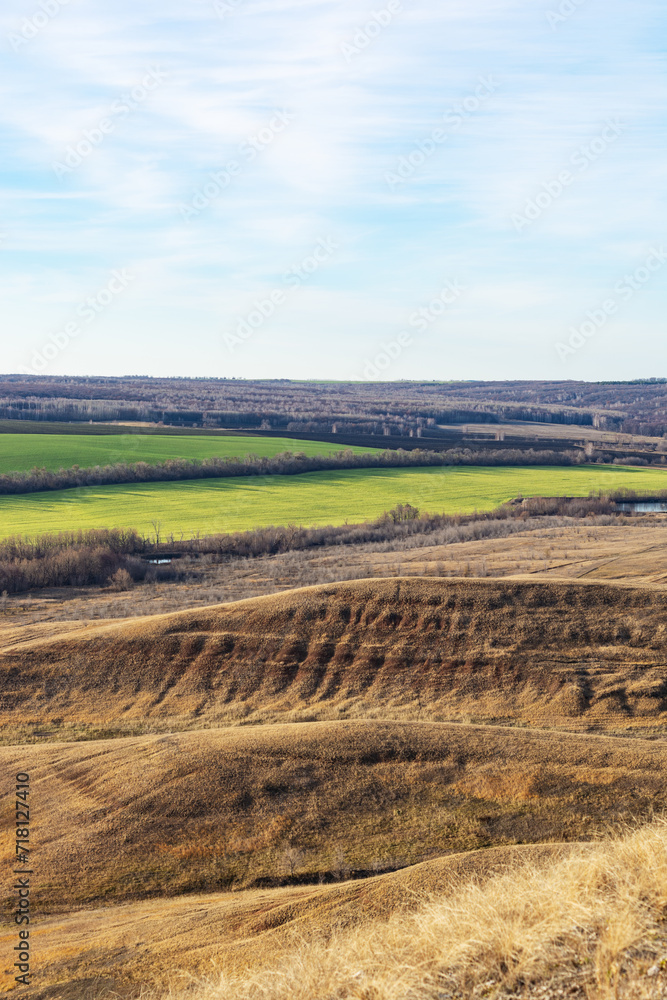 View of beautiful green fields from brown hills, Russian midland nature.