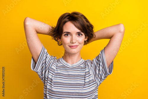 Photo of lovely pretty girl dressed trendy clothes hold hands behind head isolated on yellow color background