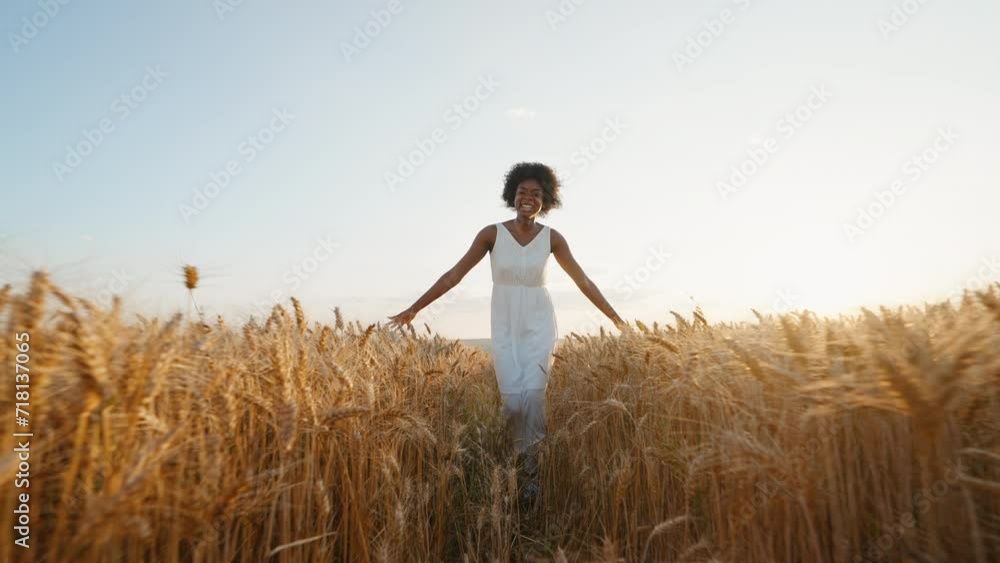 Travel concept. Graceful black woman afro hair runs in white dress across field of golden wheat towards wind smiling rejoices on walk in summer at sunset blue sky slow motion. Go Everywhere. Freedom Travel concept. Graceful black woman afro hair runs in white dress across field of golden wheat towards wind smiling rejoices on walk in summer at sunset blue sky slow motion. Go Everywhere. Freedom