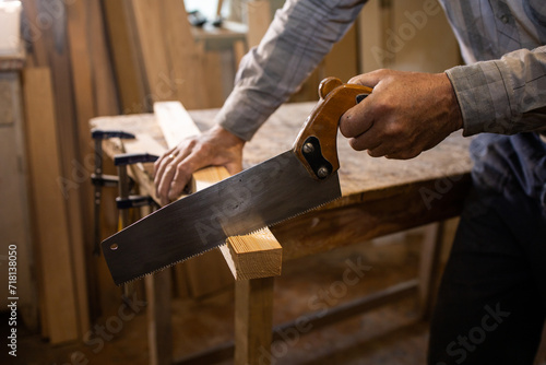 Carpenter in the workshop. Cutting wood with a saw. 