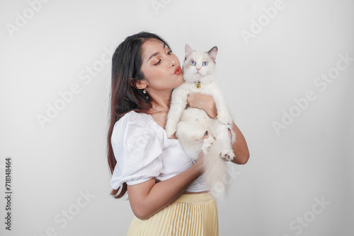 Portrait of young Asian woman holding cute ragdoll cat with blue eyes. Female hugging her cute long hair kitty isolated by white background. Adorable domestic pet concept.
