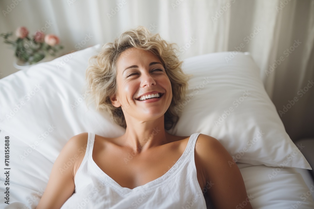 A woman smiles brightly, lying in a bed, exuding happiness and comfort in the morning light. A woman smiles brightly, lying in a bed, exuding happiness and comfort in the morning light.