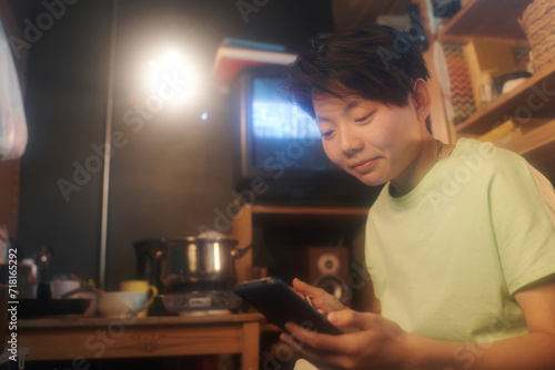 Young Chinese woman watching curious online video or looking through posts in social networks while having lunch in small apartment