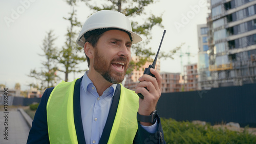 Caucasian aggressive annoyed worker man in hardhat angry mad furious architect engineer contractor shouting screaming trouble problem dissatisfied repairman in city building yelling on walkie talkie
