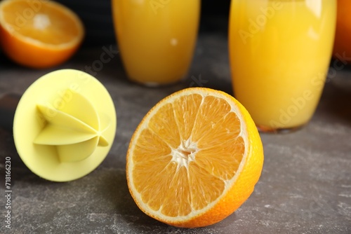 Cut fresh ripe orange, reamer and juice on grey table, closeup photo