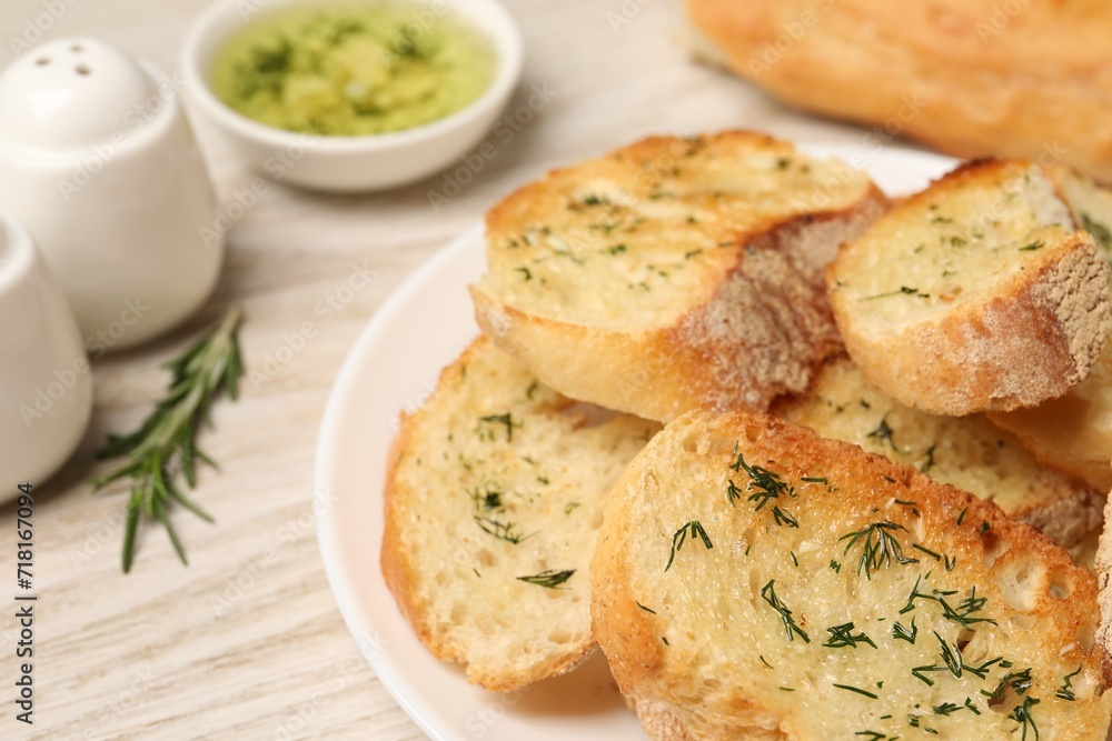 Tasty baguette with garlic and dill on white table, closeup Tasty baguette with garlic and dill on white table, closeup