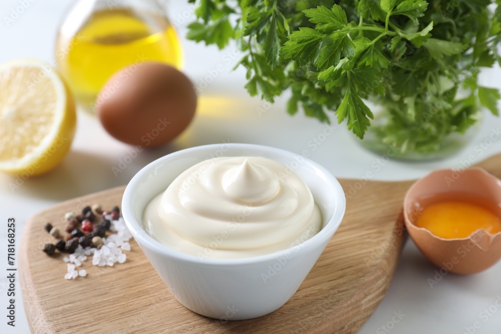 Tasty mayonnaise sauce in bowl, spices and ingredients on white table, closeup Tasty mayonnaise sauce in bowl, spices and ingredients on white table, closeup