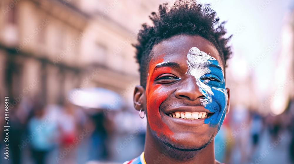 A joyful young dark-skinned guy with a face painted in the blue and red colors of the French flag welcomes the event A joyful young dark-skinned guy with a face painted in the blue and red colors of the French flag welcomes the event