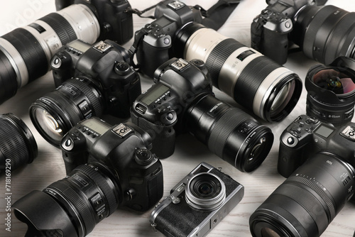 Modern cameras on white wooden table, closeup