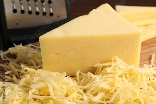 Grated and whole piece of cheese on wooden board, closeup