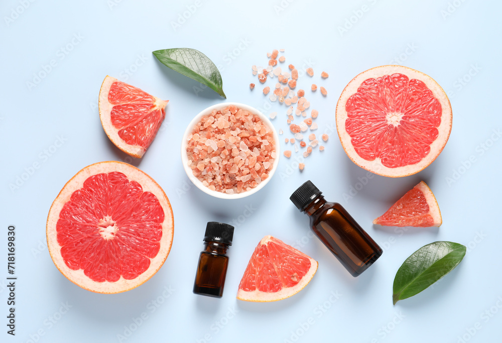 Grapefruit essential oil in bottles, sea salt and cut fruit on light blue table, flat lay Grapefruit essential oil in bottles, sea salt and cut fruit on light blue table, flat lay