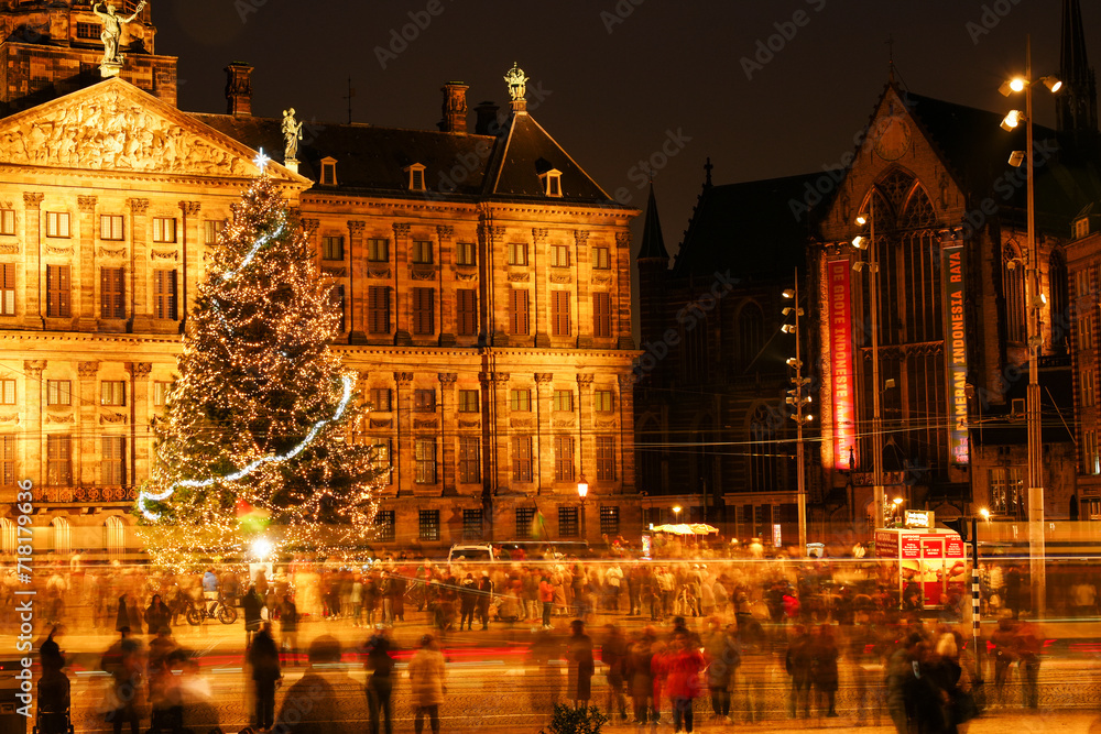 Dam 2, 1012 NP Amsterdam, Netherlands - December 25, 2023: Christmas tree on Dam Square. Long exposure shot. Bluried crowd of people on the middle-ground.