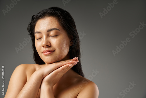 Obraz na plátně young and brunette asian woman with acne prone skin posing with closed eyes on g