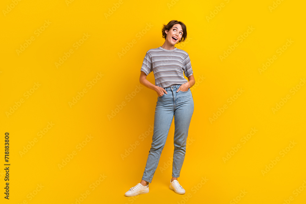 Full length photo of cheerful adorable girl dressed stylish clothes looking empty space offer poster isolated on yellow color background Full length photo of cheerful adorable girl dressed stylish clothes looking empty space offer poster isolated on yellow color background