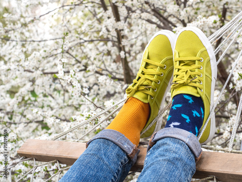 Trendy sneakers and colorful socks on the background of flowering trees. Closeup, outdoors. Men's and women's fashion style. Beauty and elegance concept