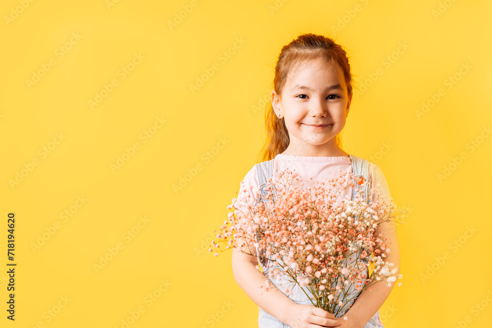 Girl holding dried flowers in her hands against a yellow background. Girl holding dried flowers in her hands against a yellow background.