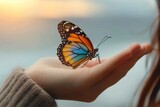 A woman holds a delicate monarch butterfly on her hand, admiring its vibrant colors and marveling at the beauty of nature