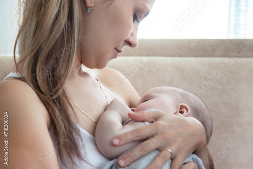 Close up cute mum breastfeeding newborn baby sitting on chair at home, in bedroom. Woman care mother nursing baby in room, caring newborn kid. Concept of motherhood, maternity. Copy ad text space