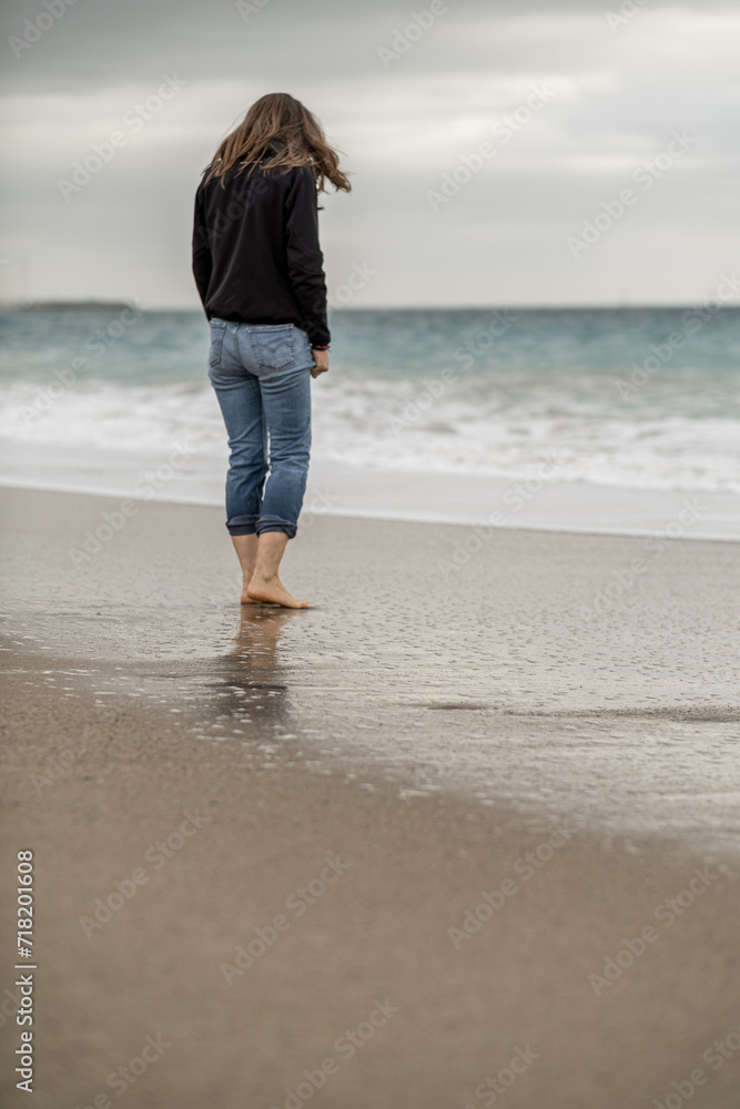 Woman standing alone barefoot on the foreshore.