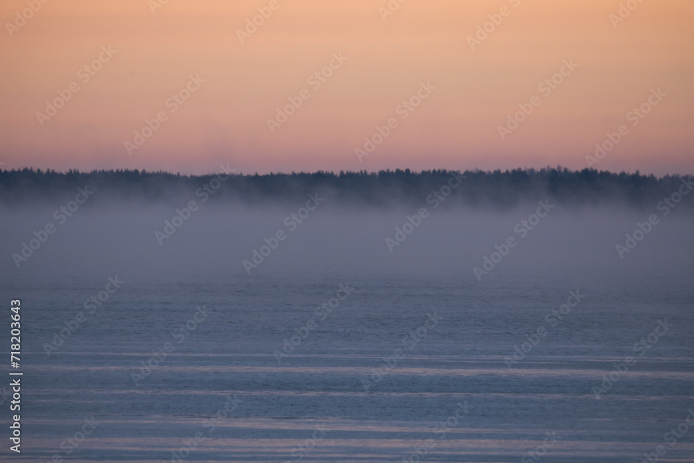 Fototapeta premium Sea winter landscape at sunrise, steam from the water.