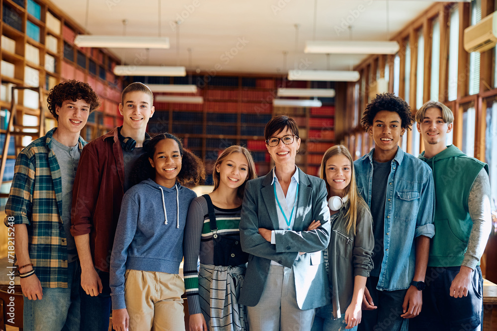 Happy high school teacher and her students in library looking at camera.