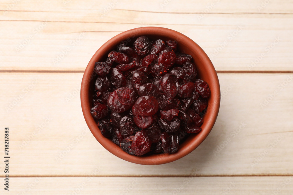 Tasty dried cranberries in bowl on light wooden table, top view Tasty dried cranberries in bowl on light wooden table, top view