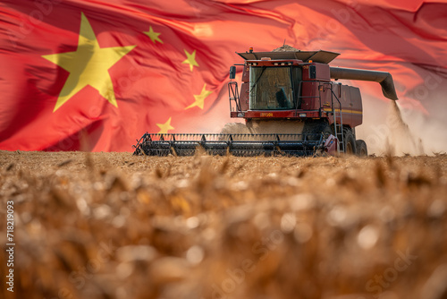 Combine harvester harvests crops against the background of the Chinese flag