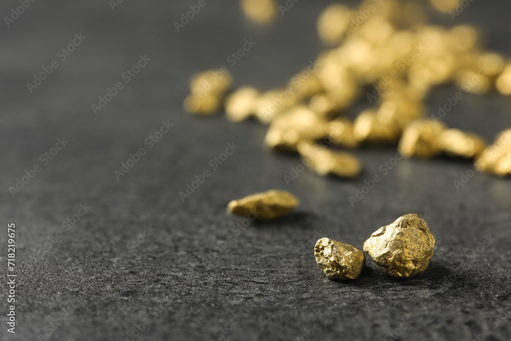 Shiny gold nuggets on grey textured surface, closeup. Space for text Shiny gold nuggets on grey textured surface, closeup. Space for text
