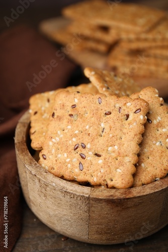 Cereal crackers with flax and sesame seeds in bowl on wooden table  closeup