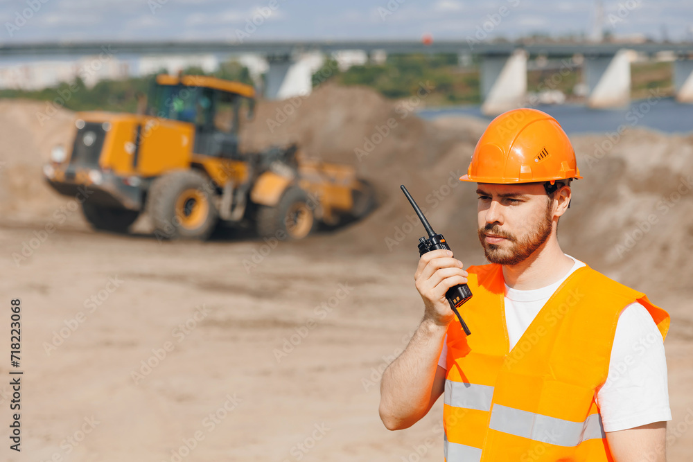 Industrial worker man of sand quarry use walkie talkie background yellow mining excavator. Concept open pit mine industry Industrial worker man of sand quarry use walkie talkie background yellow mining excavator. Concept open pit mine industry