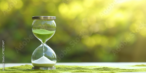 Hourglass in front of a nature background, spring and vacation atmosphere, time passing, environmental issues, responsible environmental dates, Ecological concept photo