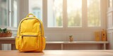 Yellow wooden table with empty space for decor and blurry window backdrop with a school backpack.