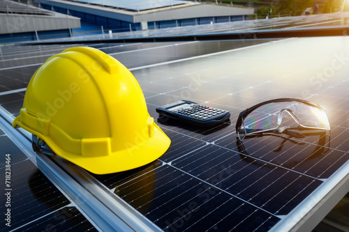 Fototapeta Naklejka Na Ścianę i Meble -  Safety Equipment on Solar Panel, Yellow Helmet, Glasses and Calculator of Employee.