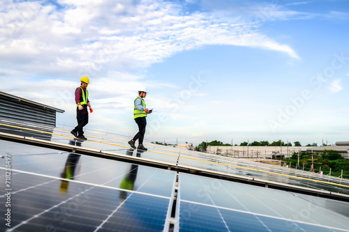 Two energy engineers are inspecting the solar panel installation on the roof for safety and performance standards. Controlling Cutting-Edge Technology for Clean, Green Energy Solutions.