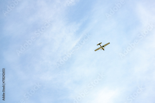 Single engine ultralight plane flying in the blue sky with white clouds. Small private plane flying in light white clouds, bottom view. Light aircraft in the sky with clouds, minimalistic style photo