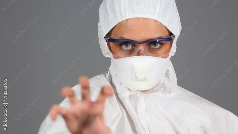 Girl in chemical protection suit shows hand gesture like a claw Girl in chemical protection suit shows hand gesture like a claw