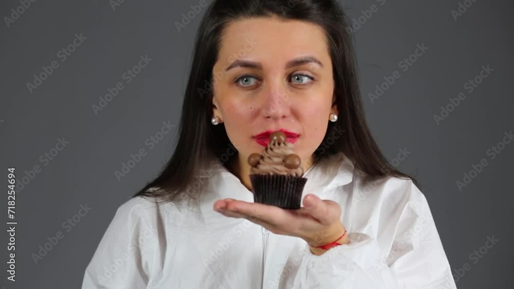 Beautiful girl dressed chemical protection smelling a cupcake Beautiful girl dressed chemical protection smelling a cupcake