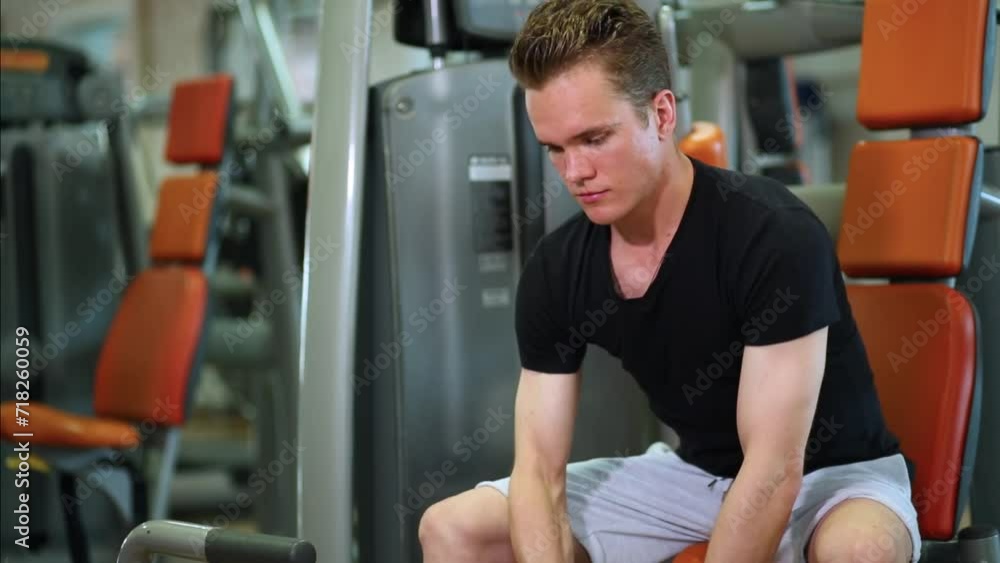 Young man sitting and raising dumbbell in right and then left hands Young man sitting and raising dumbbell in right and then left hands