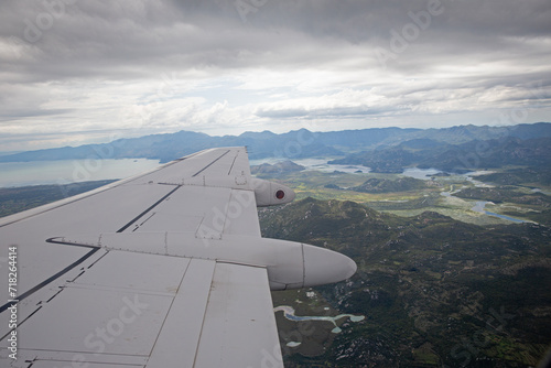 Aerial view by the airplane wing while flying above the beautiful Montenegro landscape before landing at the Podgorica airport, wide angle shot