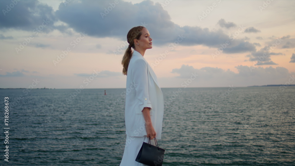 Elegant woman enjoy seascape standing in front cloudy sky. Lady looking sunset Elegant woman enjoy seascape standing in front cloudy sky. Lady looking sunset