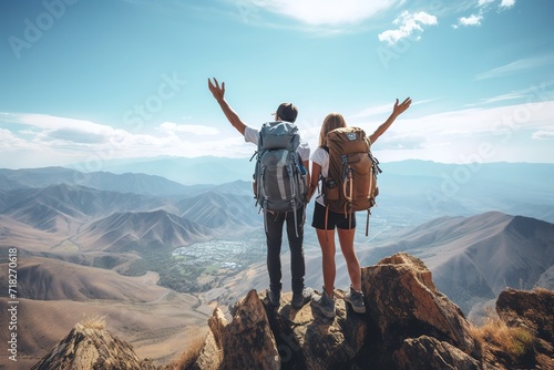 Backpackers couple stand on the top of the mountain with their bags on their backs, overlooking the beautiful scenery, low angle shot. Travel and adventure, hiking. Success concept