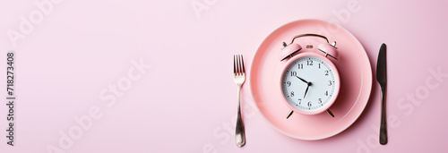 pink alarm clock in a plate with a fork for breakfast photo