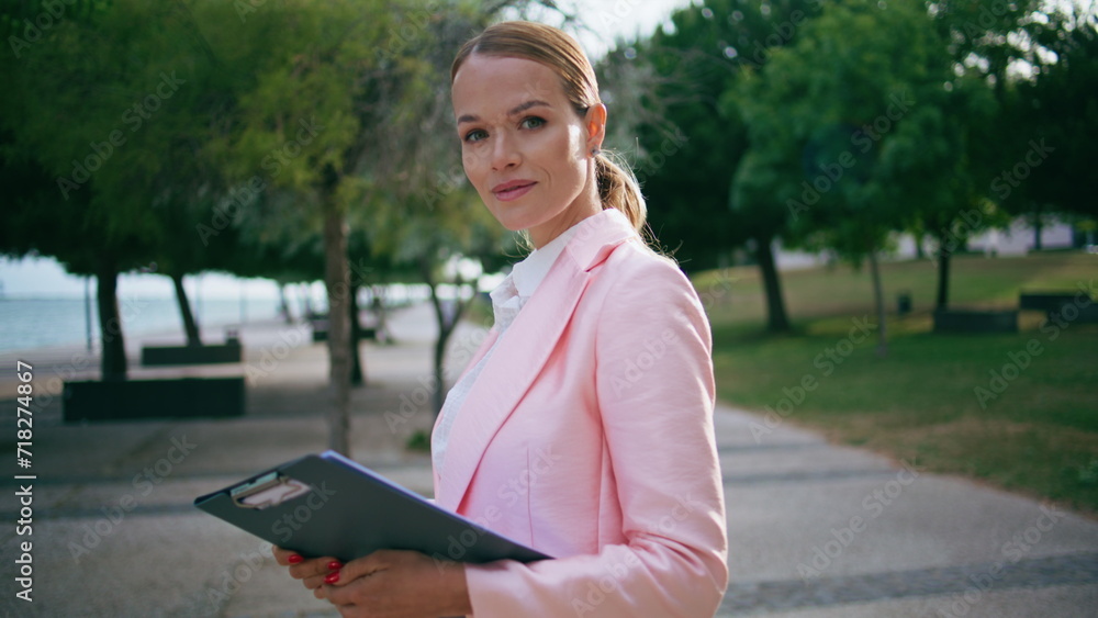 Fototapeta premium Closeup happy businesswoman posing in green city park with documents folder.